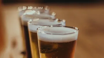 Reihe von Biergläsern auf Holztisch.