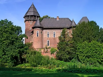 Eine Burg umgeben von üppigem Grün und Bäumen.