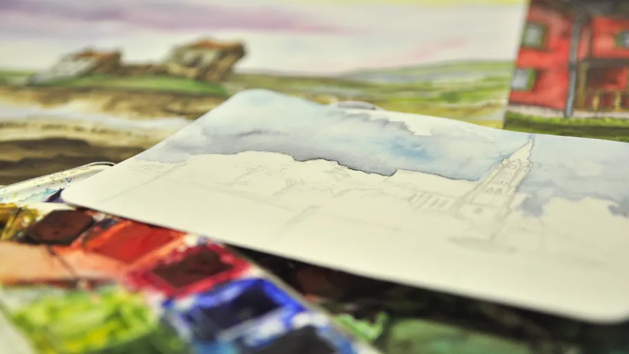 Watercolor sketches on a table with paint palette.