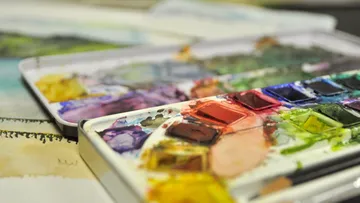 Open watercolor palette on an artistic table.