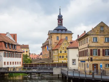 Historic buildings along a river under cloudy skies.