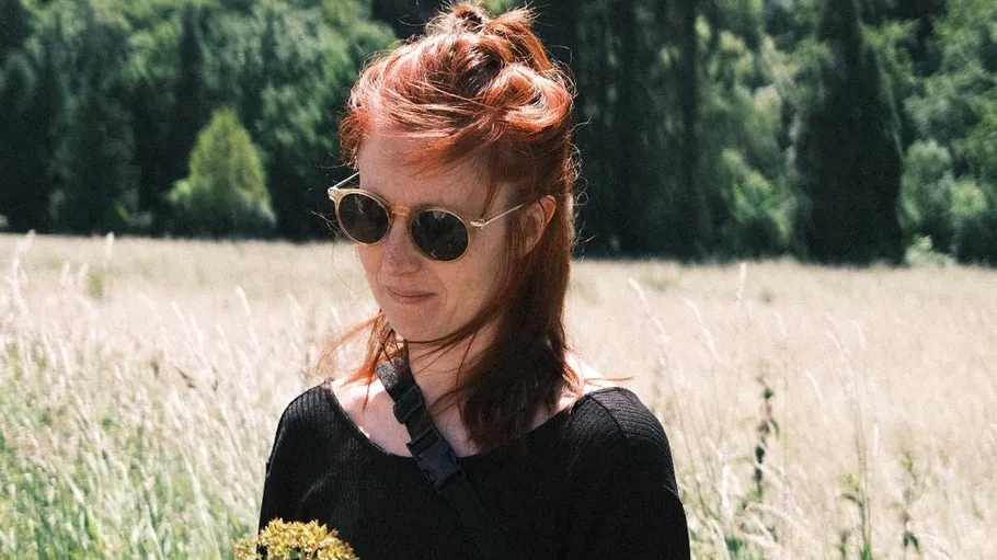 Person mit Sonnenbrille im Grasfeld gehend.