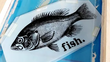 Illustrierter Fisch auf Folie, Text 'Fisch'.