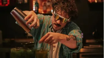 Barkeeper mixt Getränke in einer dunklen Bar.