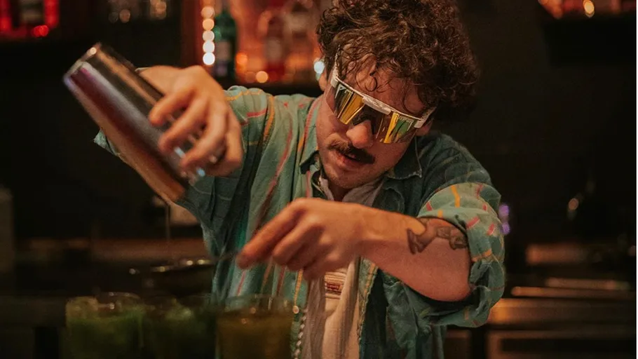 Barkeeper mixt Getränke in einer dunklen Bar.