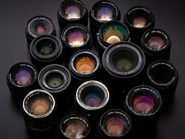 Various camera lenses lie on a dark background.