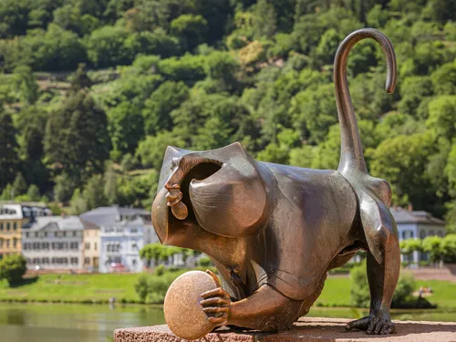 Bronzeskulptur eines katzenartigen Wesens, das einen Ball hält.