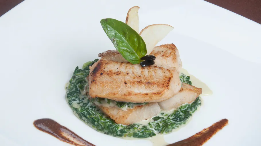 Gegrillter Fisch auf Rahmspinat, elegant garniert.