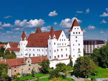 Weißes Schloss mit rotem Dach in grünem Umfeld.