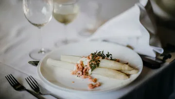 Spargel mit Garnelen auf weißem Teller, elegantes Gedeck.