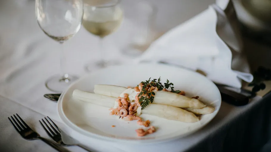 Asparagus with shrimp on white plate, elegant setting.