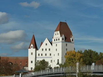 Schloss mit roten Dächern steht unter blauem Himmel.