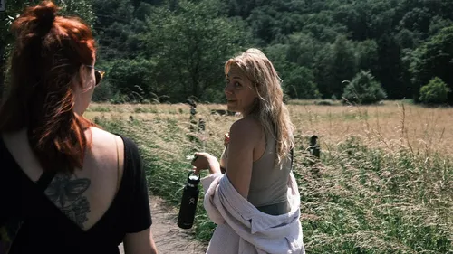 Zwei Frauen gehen durch ein grasiges Feld.