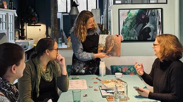 Woman showing art book to three interested women.
