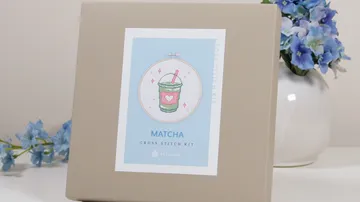 Cross-stitch kit with matcha design on table.