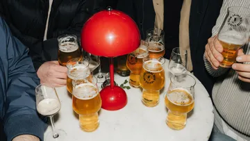 Biergläser auf einem Tisch um eine rote Lampe.