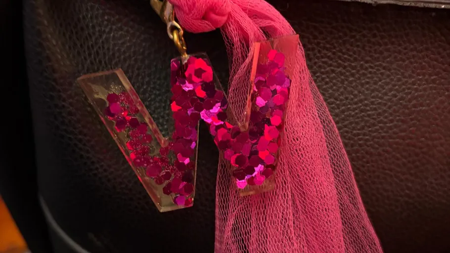 Letter 'W' keychain with glitter on bag.