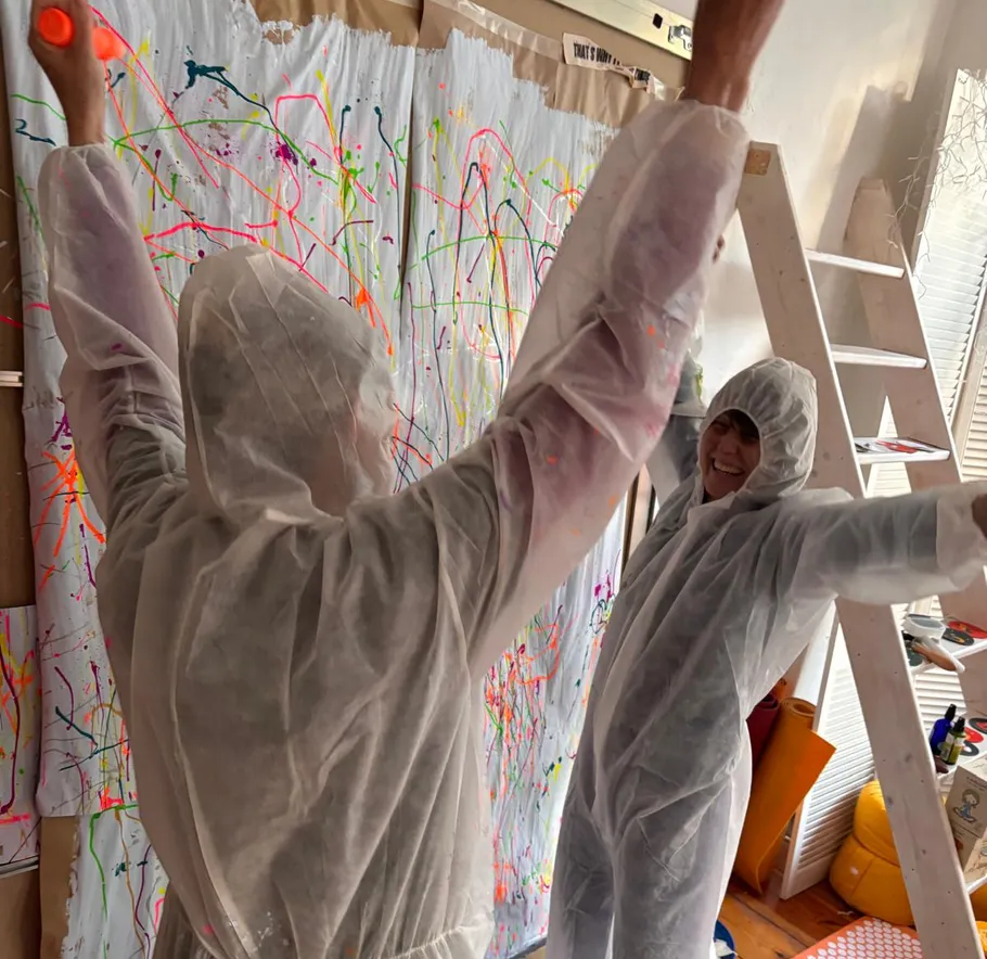 People in white suits painting abstract art.