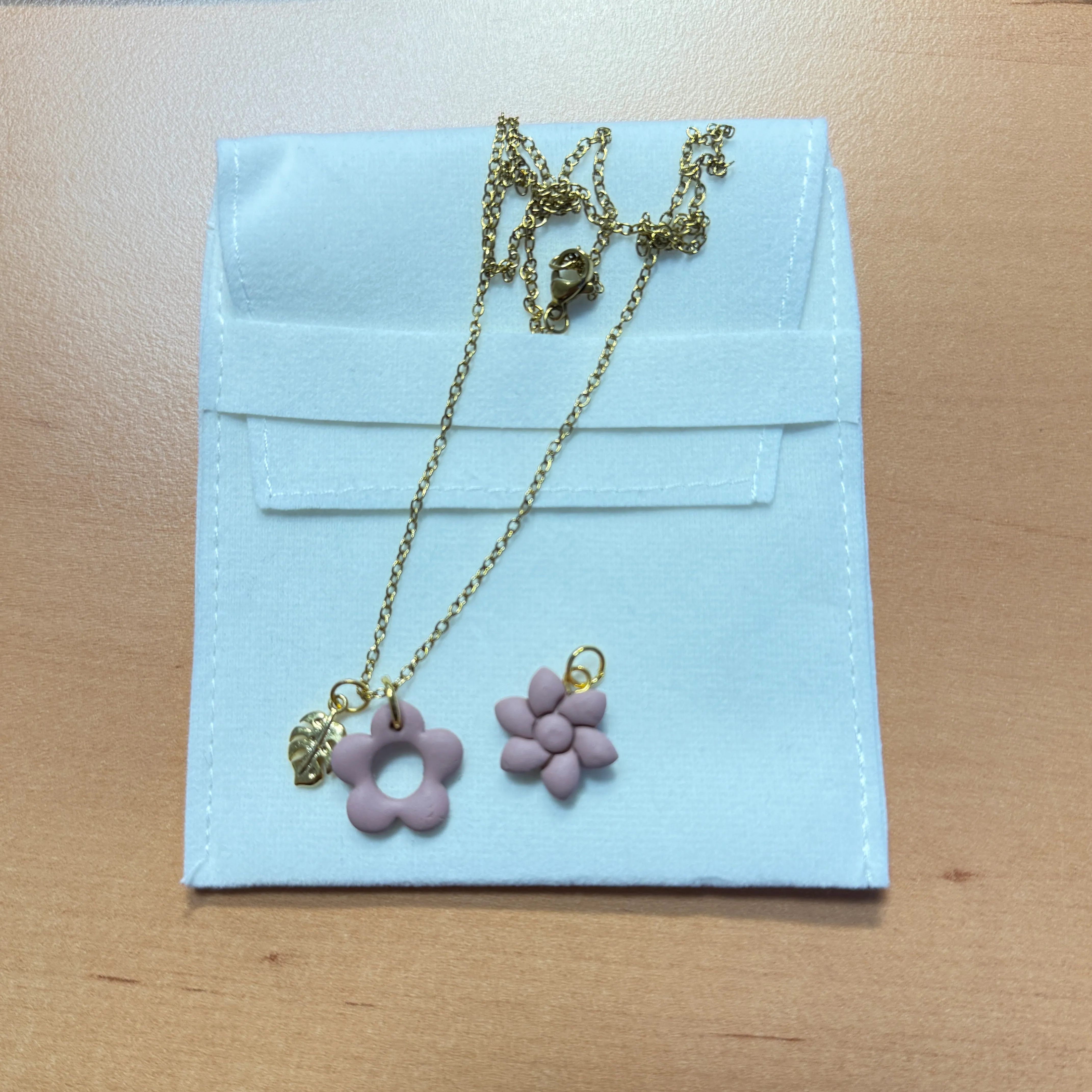 Gold necklace with lavender flower charms on pouch.