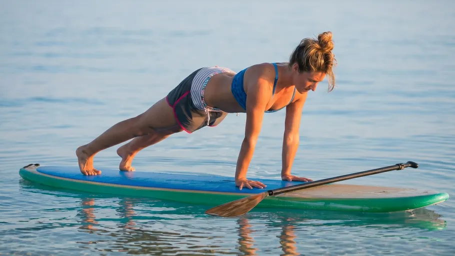 Person macht Yoga-Planke auf Paddleboard im Wasser.