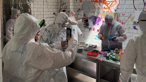 Menschen in Schutzanzügen malen Graffiti drinnen.