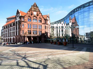 Historisches Gebäude und moderne Glasfassade stehen gegenüber.