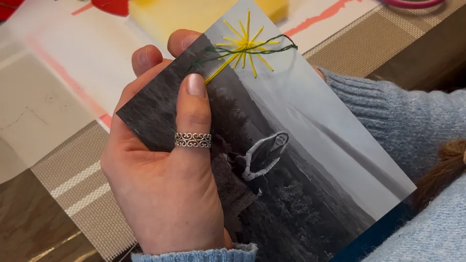 Hand holding a photo with embroidery design.