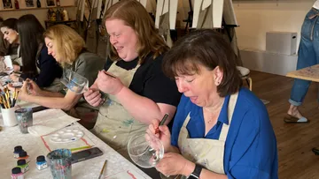 Women painting glasses in an art class.