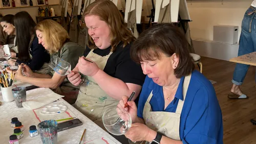 Women painting glasses in an art class.
