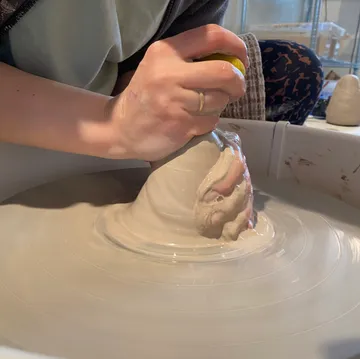 Person shaping clay on a spinning pottery wheel.