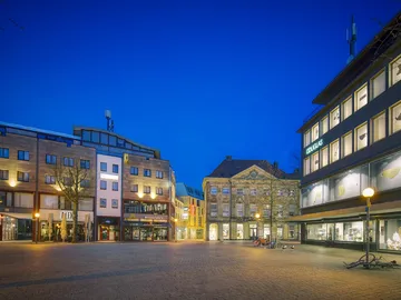 Stadtplatz bei Nacht mit modernen und historischen Gebäuden.