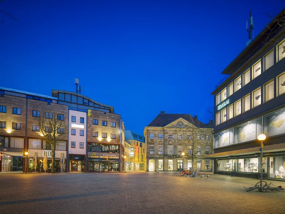 Stadtplatz bei Nacht mit modernen und historischen Gebäuden.