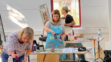 Artists painting in a bright studio.