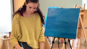 Woman painting on canvas in art studio.