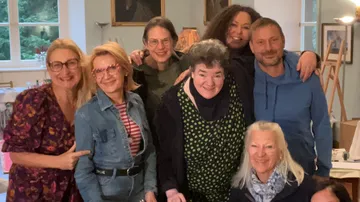 Gruppe von Menschen lächelt drinnen bei einem Treffen.