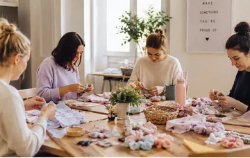 Frauen basteln am Tisch mit Stoffblumen.