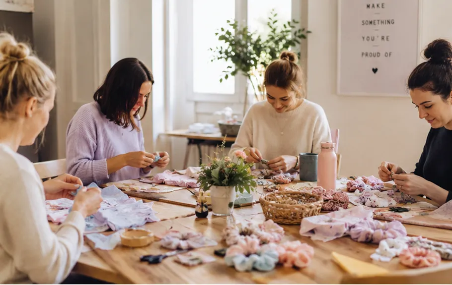 Frauen basteln am Tisch mit Stoffblumen.