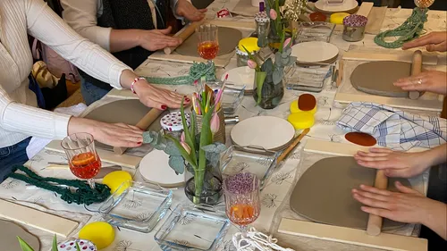 Personen basteln mit Nudelholz am Tisch.