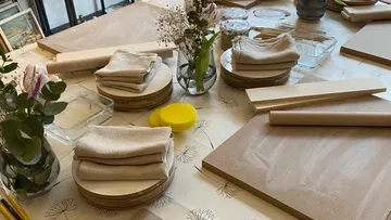Pottery workshop table with tools and flowers.