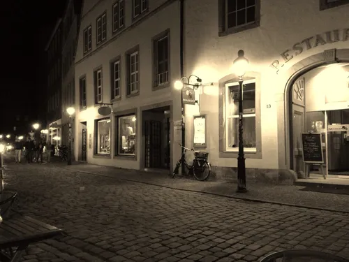 Dark street with illuminated buildings and bikes.