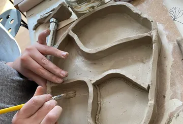 Person shaping clay into divided tray.