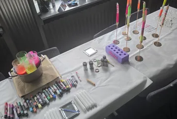Basteltisch mit bunten Kerzen und Markern.