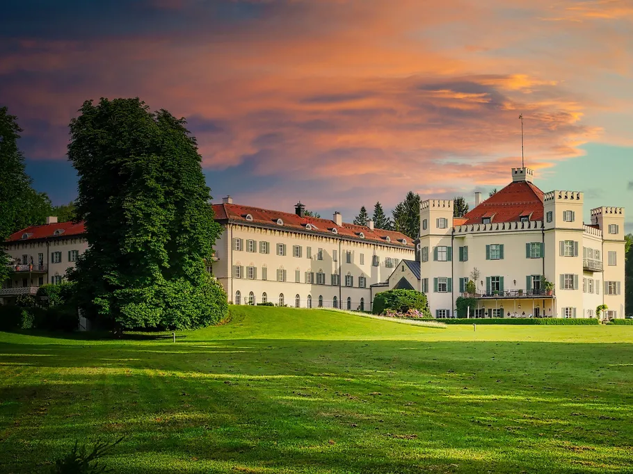 Castle stands on a green lawn under a colorful sky.