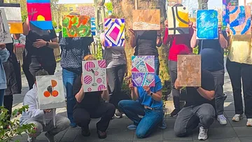 People displaying abstract art in a group outdoors.