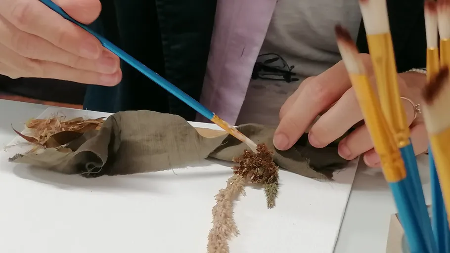 Person using brush on fabric with plant.
