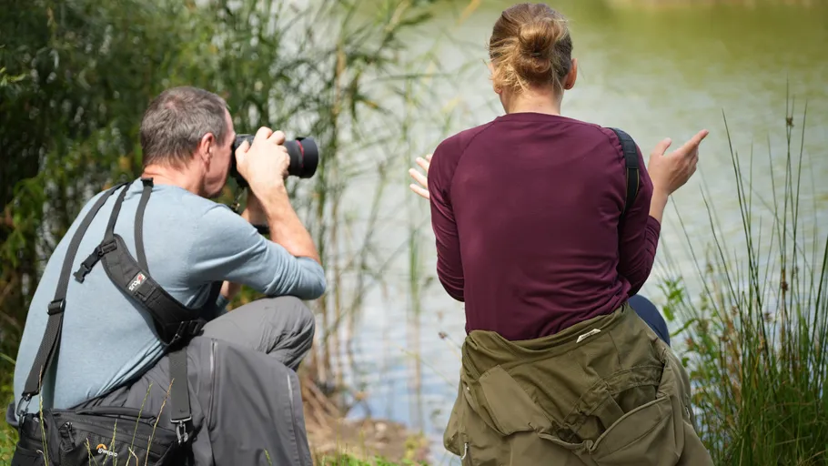 Mann fotografiert Frau am See.