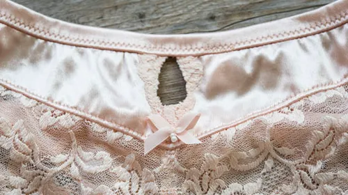 Pink lace garment with bow and keyhole design.