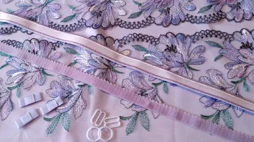 Spitzenstoff mit Blumen, Bändern und Haken.