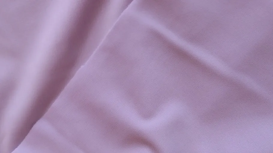 Rosa Stoff mit leichten Falten auf Oberfläche.
