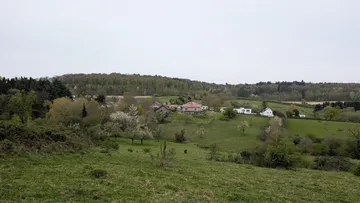 Houses on hillside surrounded by green fields.